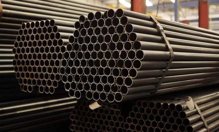 Tubos de aço redondos organizados em feixes industriais, representando diferentes tipos de tubos de aço usados em estruturas metálicas.